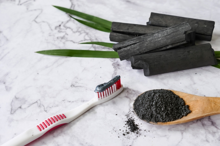 Toothpaste by activated charcoal powder on marble table shutterstock_1150775072